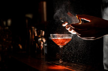 Bartender Sprays An Orange Peel In Cocktail Glass