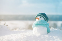 Little Snowman In A Cap And A Scarf On Snow In The Winter. Festive Background With A Lovely Snowman. Christmas Card, Copy Space