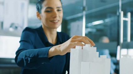 Poster - Female Architectural Designer Adds Component to a Building Model, She Works on a City District Urban Planning Project. Beautiful Woman in Stylish Office. Shot on RED EPIC-W 8K Helium Cinema Camera.