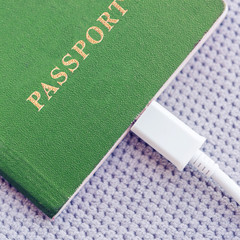 Wall Mural - Green Passport with a white cable connected on a gray textile background