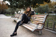 © ADDICTIVE STOCK - Stylish woman sitting on bench
