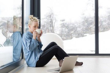 woman drinking coffee and using laptop at home