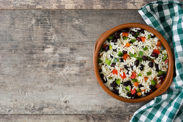 Wall Mural - Traditional cuban rice, black beans and pepper on wooden table background. Moros y cristianos.