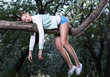 Wild fatigue. Beautiful young woman sleeping on a tree branch. Feet and hands hanging down