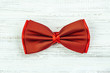 Red bow tie on a wooden background. Accessory for formal dress. Symbol of elegance and fashion for men.