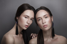 Fashion Portrait Of Two Beautiful Slim Sexy Young Girls Twins Sisters With Clear Pink Nude Natural Make-up And Black Earings