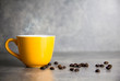 © ittipol - yellow cup of coffee and coffee bean with concrete background