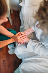 Wall Mural - Female doctor giving encouragement to elderly patient by holding her hands