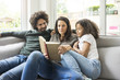 © Westend61 - Happy family sitting on couch, reading book