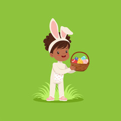 Sticker - Beautiful little girl with bunny ears and rabbit costume standing with basket full of painted eggs, kid having fun on Easter egg hunt vector Illustration