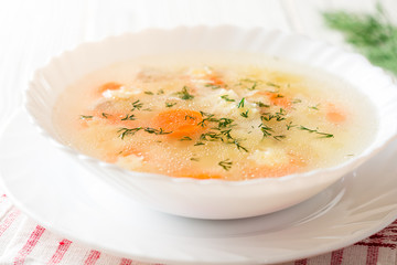 Wall Mural - Chicken soup with stelline pasta and carrot on white wooden table.