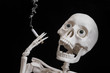 The skeleton smokes a cigarette while enjoying tobacco smoke. Idea: harm of smoking, motivation to quit, harm, slow death
