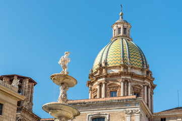 View of San Giuseppe dei Teatini church dome with statue of the Pretoria fountain ahead in Palermo, Sicily, Italy