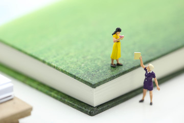 Miniature people : sitting on book using as background education or business concept.