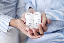 Man And Pregnant Women Holding Baby Shoes