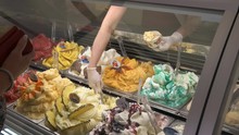 A Sales Assistant Scoops Out Frozen Gelato From A Display Cabinet In Rome, Italy