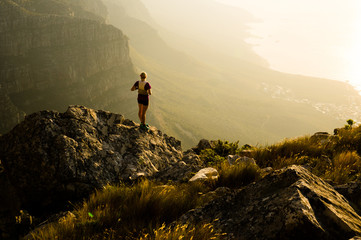 a young lady trail runner watching the sunset from a mountain top on the cape peninsula of south afr
