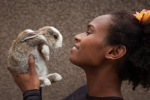 Idealistic Young Afro American Woman Daydreaming With Easter Bunny Rabbit In Her Hands, Feeling Blessed 