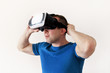 © zoranlino - Man wearing and playing mobile game app on device virtual reality glasses on white background. Man action and using in virtual headset, VR box for use with smart phone. Contemporary technology concept