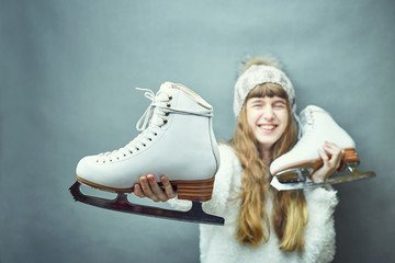 Wall Mural - A girl with skates in her hands in a white sweater and hat.