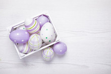 Top View Of Purple Easter Eggs In White Basket. Easter Background With Copy Space