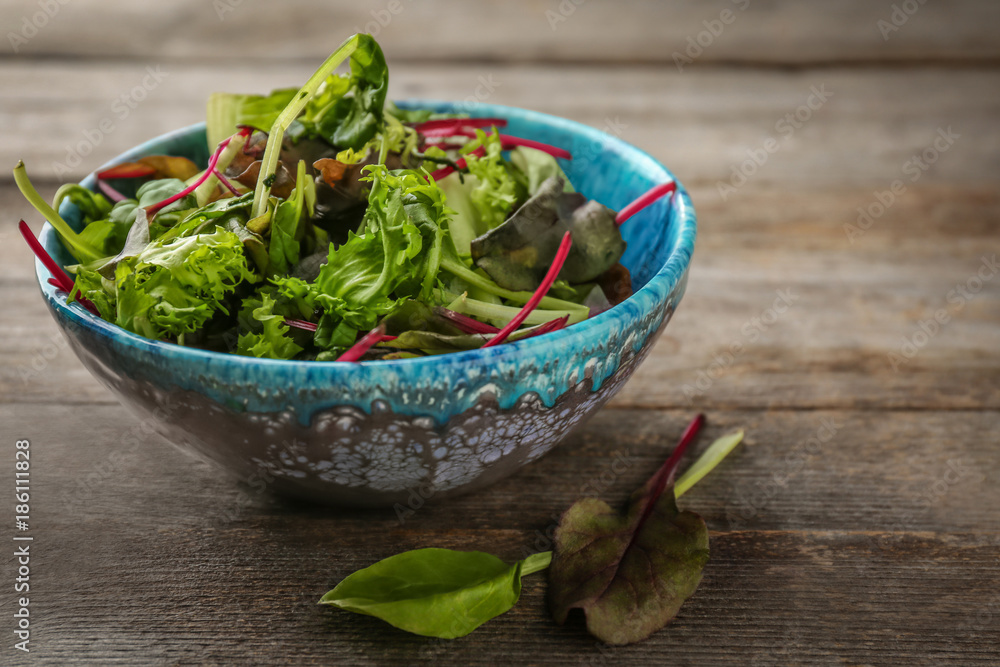 Bowl of fresh salad on wooden table