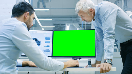 Industrial Designer Has Conversation with Senior Engineer While Working in CAD Program, One Has a Green Screen Chroma Key Template Great for Mockup. He Works on Personal Computer with Two Monitors.