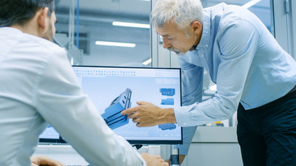 Industrial Designer Has Conversation with Senior Engineer While Working in CAD Program, Designing New Component. He Works on Personal Computer with Two Monitors.