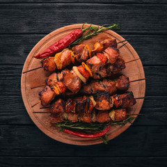 Shish kebab on skewers with onions. On the black wooden table.