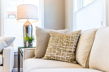 Closeup Of Two Pillows On Couch Or Sofa By Bright Window In Modern Apartment, House Or Home With Staging Of Large Beige, Neutral White Colors, Lamp