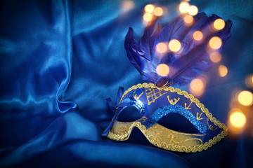 Image of elegant venetian mask over blue silk background.