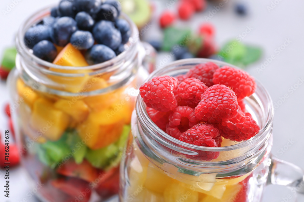 Mason jar with fruits and berries on table, closeup