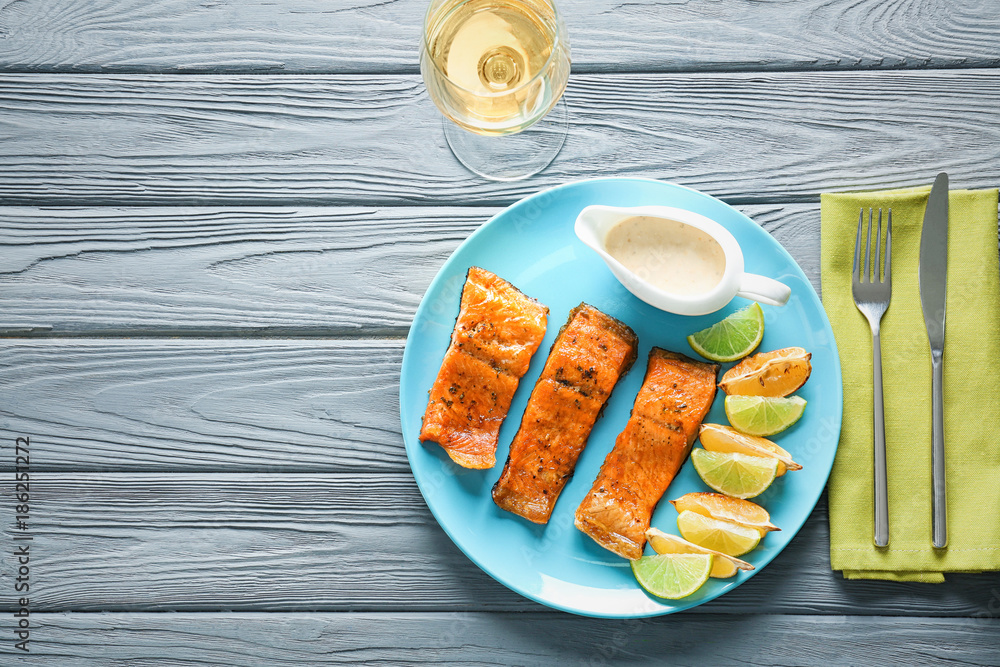 Delicious fried rainbow trout with lime, lemon and sauce on plate, top view