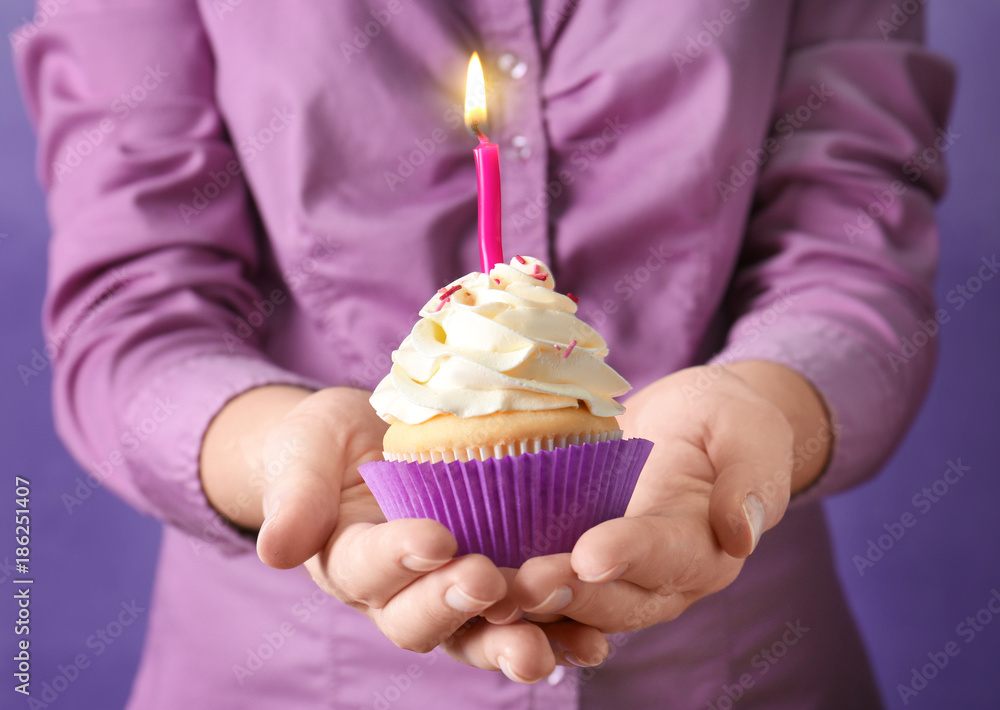 Woman holding cupcake with candle, close up