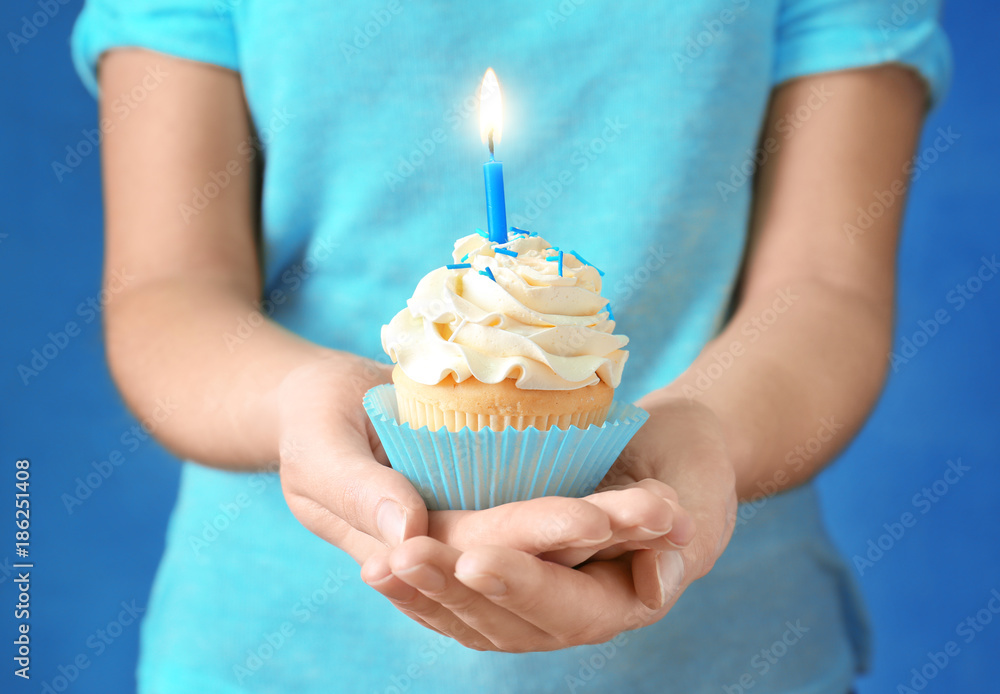 Woman holding cupcake with candle, close up