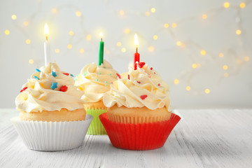 Sticker - Tasty cupcakes with candles on wooden table