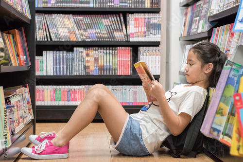 Children's education lifestyle with school girl kid reading book sitting on the Tableau sur Toile