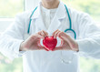 Cardiovascular disease doctor or cardiologist holding red heart in clinic or hospital exam room office for professional medical and cardiology health care service and world heart health day concept