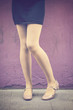 Woman legs with pastel yellow panties and mary jane shoes over a violet wall background - Funny tights and flat shoes - Female legs in a fashion, cute, retro stylish look