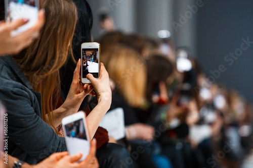 Fotomural Woman making photo on smatrphone while watching fashion show