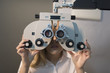 Woman ready for eye test with phoropter and calibrating glasses