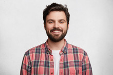 Smiling Bearded Young Male Model Rejoices Coming Weekends, Dressed Casually, Isolated Over White Background. Positive Pleased Student Being In Good Mood After Successfully Passed Exams At College
