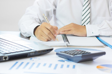 Wall Mural - businessman writing and memory on notebook and calculator on table, accountant and business concept.