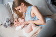 Mother lying on bed and breast feeding baby. She is looking at child with tenderness and stroking on the hand