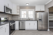 Kitchens In White New, With Granite Counter-tops, Stove And Stainless Steel Refrigerator.