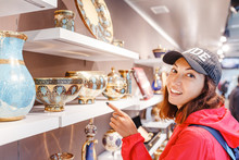 Tourist Woman Choosing Ornamental Ceramic Dishes In Souvenir Shop