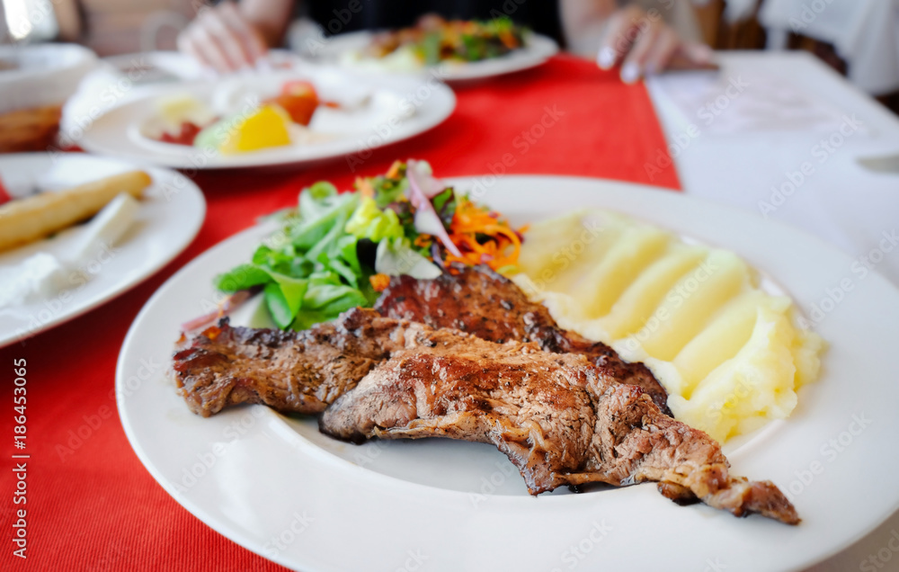 Plate with tasty mashed potatoes, fried meat and salad on table, closeup
