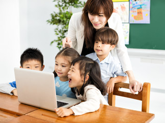 Wall Mural -  children looking at the laptop with teacher near by