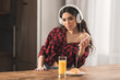 © LIGHTFIELD STUDIOS - girl in checkered shirt wearing headphones and using smartphone while having breakfast at home