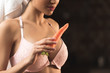 © LIGHTFIELD STUDIOS - cropped shot of sexy young woman in bra and towel holding carrot on black
